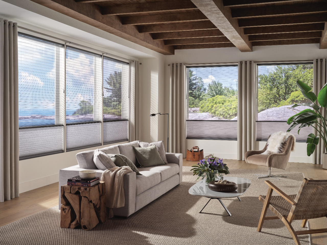 Living room with a sofa, coffee table, and accent chair set in front of large windows with Duette Honeycomb Shades.